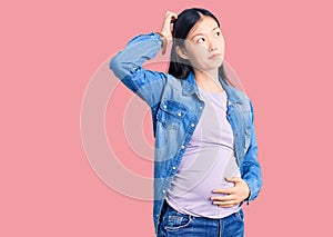 Young beautiful chinese woman pregnant expecting baby confuse and wondering about question