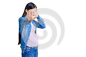 Young beautiful chinese woman pregnant expecting baby covering eyes with hands and doing stop gesture with sad and fear expression