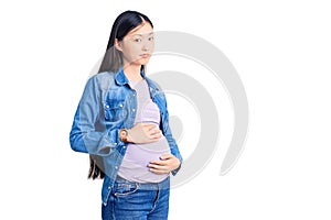 Young beautiful chinese woman pregnant expecting baby looking sleepy and tired, exhausted for fatigue and hangover, lazy eyes in