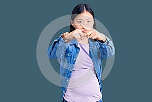 Young beautiful chinese woman pregnant expecting baby rejection expression crossing fingers doing negative sign