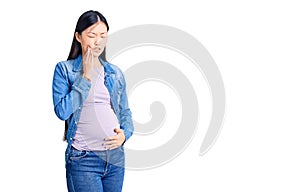 Young beautiful chinese woman pregnant expecting baby touching mouth with hand with painful expression because of toothache or