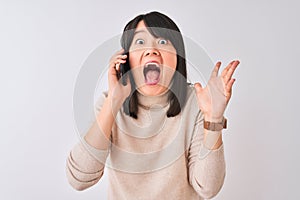 Young beautiful Chinese woman talking on the smartphone over isolated white background very happy and excited, winner expression