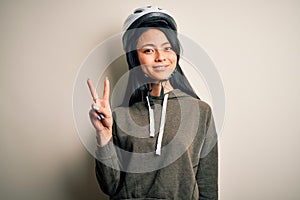 Young beautiful chinese woman wearing bike helmet over isolated white background showing and pointing up with fingers number two