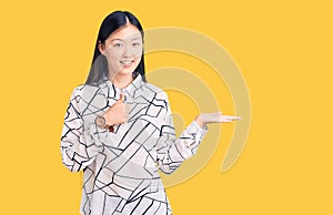 Young beautiful chinese woman wearing casual shirt showing palm hand and doing ok gesture with thumbs up, smiling happy and