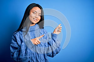 Young beautiful chinese woman wearing casual sweater over isolated blue background smiling and looking at the camera pointing with