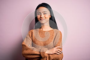Young beautiful chinese woman wearing casual sweater over isolated pink background happy face smiling with crossed arms looking at