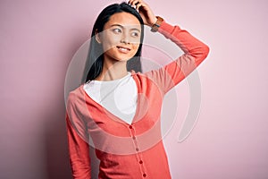 Young beautiful chinese woman wearing casual sweater over isolated pink background smiling confident touching hair with hand up