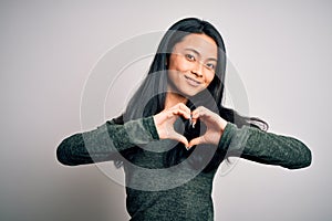 Young beautiful chinese woman wearing casual t-shirt over isolated white background smiling in love showing heart symbol and shape
