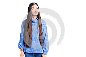 Young beautiful chinese woman wearing casual turtleneck sweater smiling looking to the side and staring away thinking