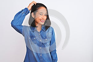 Young beautiful chinese woman wearing denim shirt standing over isolated white background confuse and wonder about question