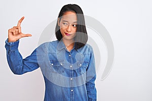 Young beautiful chinese woman wearing denim shirt standing over isolated white background smiling and confident gesturing with