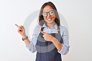 Young beautiful chinese woman wearing glasses and apron over isolated white background smiling and looking at the camera pointing