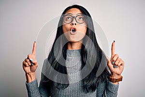 Young beautiful chinese woman wearing glasses and sweater over isolated white background amazed and surprised looking up and