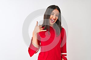 Young beautiful chinese woman wearing red dress standing over isolated white background smiling doing phone gesture with hand and