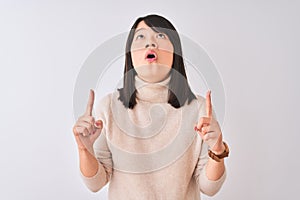 Young beautiful chinese woman wearing turtleneck sweater over isolated white background amazed and surprised looking up and