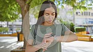 Young, beautiful, and confident, a portrait of a smiling hispanic woman enjoying time in her watch at a green city park