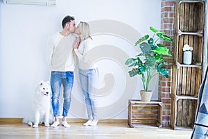 Young beautiful couple with dog kissing standing at new home