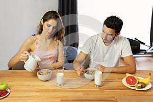 Young beautiful couple eats breakfast cereal with berries and milk