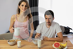 Young beautiful couple eats breakfast cereal with berries and milk