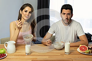 Young beautiful couple eats breakfast cereal with berries and milk