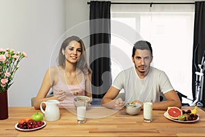 Young beautiful couple eats breakfast cereal with berries and milk