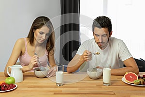 Young beautiful couple eats breakfast cereal with berries and milk