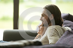 Young beautiful couple embracing relaxing on sofa together, side