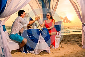 Young beautiful couple have a romantic dinner at sunset on a tropical beach . Honeymoon.