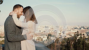 Young beautiful couple hug and kiss against the panorama of Rome, Italy. Romantic date of happy man and woman.