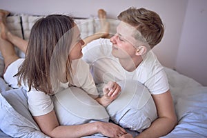 a young beautiful couple hugging and kissing in bed, wellness at home