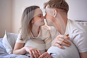 a young beautiful couple hugging and kissing in bed, wellness at home