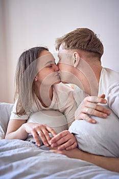 a young beautiful couple hugging and kissing in bed, wellness at home