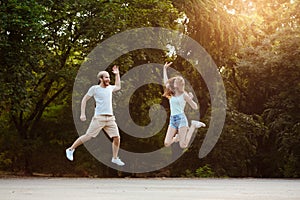 Young beautiful couple jumping, smiling, rejoicing, walking in park. Outdoor background.