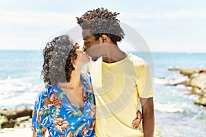 Young beautiful couple kissing and hugging standing at the beach