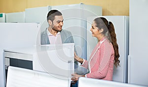 Young beautiful couple looking at large fridges