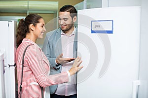 Young beautiful couple looking at large fridges