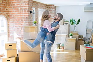 Young beautiful couple in love celebrating moving to a new home around cardboard boxes