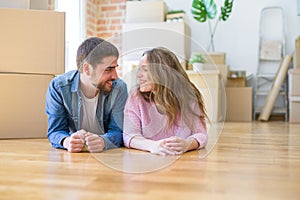 Young beautiful couple in love relaxing lying on the floor together with cardboard boxes around for moving to a new house