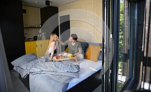 Young beautiful couple in love is sitting in bed and having healthy breakfast together.