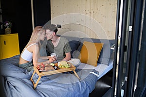 Young beautiful couple in love is sitting in bed and having healthy breakfast together.