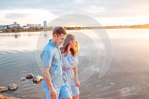 Young beautiful couple in love staying and kissing on the beach on sunset. Soft sunny colors.