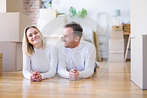 Young beautiful couple lying down on the floor at new home around cardboard boxes