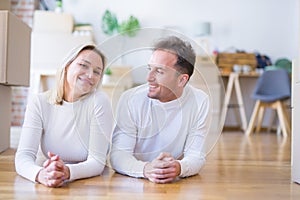 Young beautiful couple lying down on the floor at new home around cardboard boxes