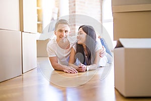 Young beautiful couple lying down at new home around cardboard boxes