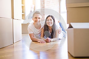 Young beautiful couple lying down at new home around cardboard boxes