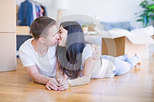 Young beautiful couple lying down at new home around cardboard boxes