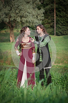 Young beautiful couple in medieval style dresses outdoor