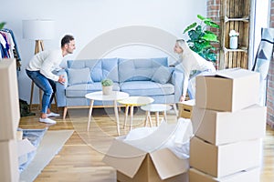 Young beautiful couple moving sofa at new home around cardboard boxes
