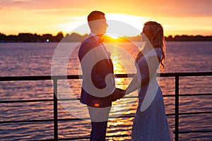 Young beautiful couple of newlyweds with bride and groom walk on the terrace by the ocean during a wedding ceremony in a wedding