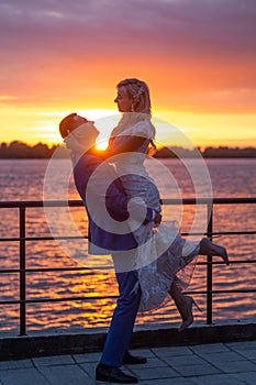 Young beautiful couple of newlyweds with bride and groom walk on the terrace by the ocean during a wedding ceremony in a wedding